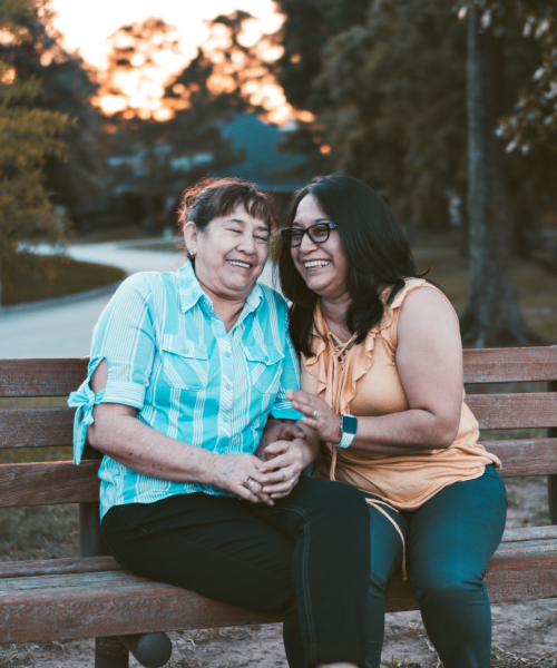 Two women talking and laughing on a park bench.